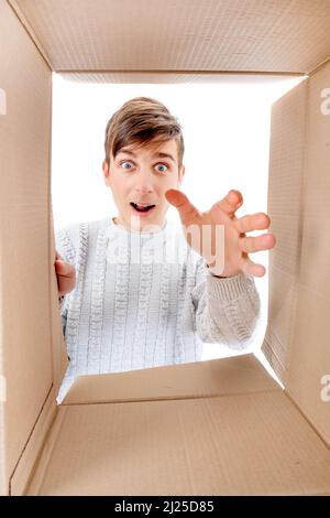 Happy and Surprised Young Man looking inside a Box and reaching a Hand Stock Photo