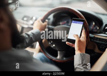 Texting and driving an accident waiting to happen. Shot of a man using his phone while driving. Stock Photo