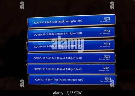 Blue NHS Covid-19 lateral flow test kit boxes / rapid lateral flow antigen coronavrus test kits against a black background Stock Photo