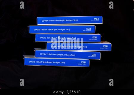 Blue NHS Covid-19 lateral flow test kit boxes / rapid lateral flow antigen coronavrus test kits against a black background Stock Photo
