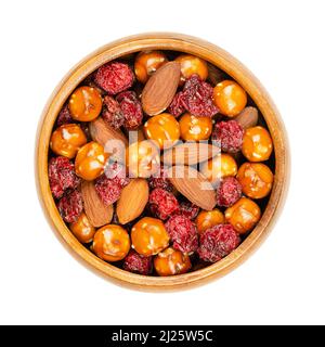 Crunchy mix, in a wooden bowl. Crunchy mix of salted pretzel balls, roasted almonds and baked cranberries. Close-up, from above. Stock Photo