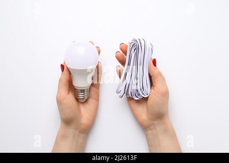 Female hands hold bulb and wire on white background Stock Photo