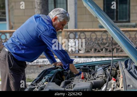 Driver looking at an engine after a breakdown in a village near Soroca, Moldova Stock Photo