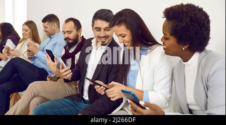 Group of happy diverse friends using mobile phones and sharing a laugh over a funny video Stock Photo