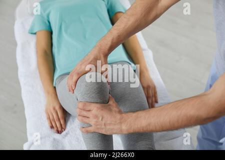 Male therapist massaging knee of female patient during physiotherapy session at the hospital. Stock Photo