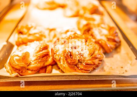 Several homemade baked Swedish cinnamon rolls or kanelbulle on a cooling rack at a cafe. Stock Photo