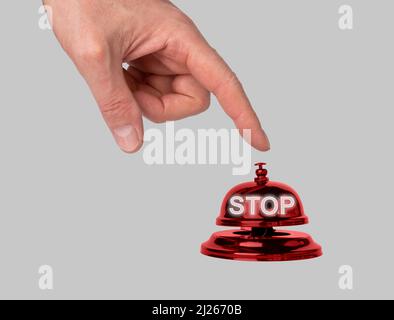 Hand pressing reception bell with word stop. Dissent, message to end violence, unemployment, injustice, pollution. Outlook and concept of policy in hotel, store, cafe, restaurant. High quality photo Stock Photo