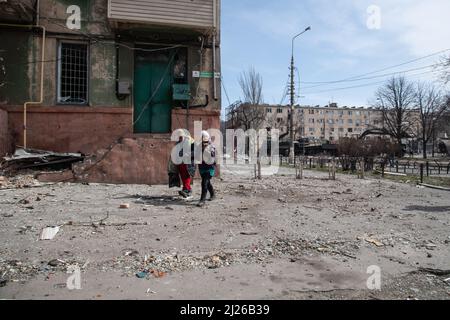 Two women with a kitten walk through a damaged neighborhood in central Mariupol in an area that was under Ukrainian control just days ago but has recently fallen under the control of Russian/Pro-Russian forces. The battle between Russian / Pro Russian forces and the defencing Ukrainian forces lead by Azov battalion continues in the port city of Mariupol. Stock Photo