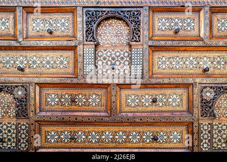 Beautiful antique inlaid wood cabinet with many drawers and compartments. Geometric arabesque patterns. Vintage design background. Stock Photo