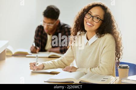Taking notes. Cropped portrait of an attractive young female college student writing in her notebook while sitting in class. Stock Photo