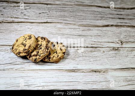 Three chocolate chip cookies isolated on rustic wooden table. Cookies. Stock Photo