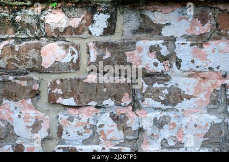 Peeling pink and white paint on old brick wall Stock Photo