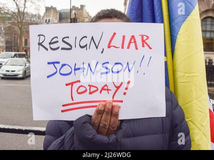 London, UK. 30th March 2022.  A protester holds a sign calling on Boris Johnson to resign. Anti-Boris Johnson, anti-Tory and anti-Brexit protesters gathered in Parliament Square as Johnson faced Prime Minister's Questions amidst fines for the Partygate scandal. Credit: Vuk Valcic/Alamy Live News Stock Photo