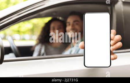 Car Rental App. Arab Couple Showing Blank Smartphone While Sitting In Auto Stock Photo