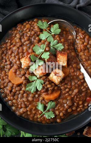 Delicious lentils soup served with toasted bread on dark table. Top view. Healthy food. Stock Photo