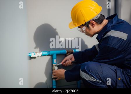 A plumber is fixing the leaked pipe outdoors. Stock Photo