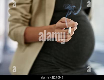 When youre pregnant, theres more than yourself to think about. Shot of a woman smoking a cigarette while preganant. Stock Photo
