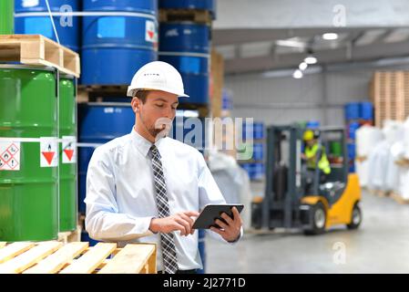 manager in a logistic company work in a warehouse with chemicals - checking goods with tablet Stock Photo