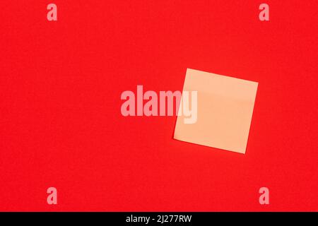 Yellow paper adhesive note stuck to a red background. Stock Photo