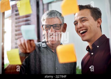 Were going to succeed big with this winning plan. Shot of two businessmen brainstorming with notes on a glass wall in an office. Stock Photo