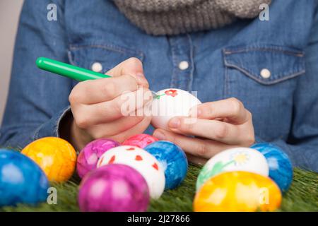 A closeup of a person drawing patterns on eggs with markers for Easter Stock Photo