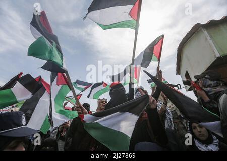 Gaza City, Palestinian Territories. 30th Mar, 2022. Palestinians wave Palestinian flags during a rally marking the 46th anniversary of the Land Day. Land Day marks an incident that took place in 1976 when Israeli troops shot and killed six people during protests against land confiscations. Credit: Mohammed Talatene/dpa/Alamy Live News Stock Photo