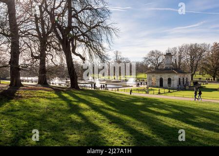 Trees cast long shadows at the Italian Gardens in Hyde Park, London on a bright and sunny winter's day. Stock Photo