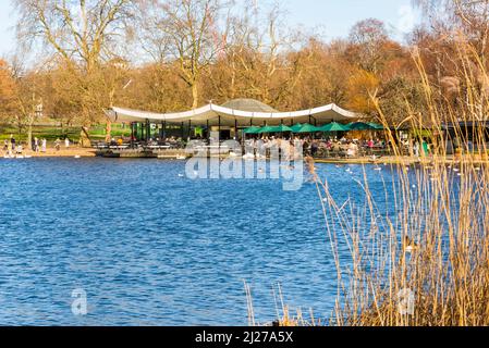 People relaxing and enjoying themselves outdoors at a cafe, the Serpentine Bar and Kitchen, in Hyde Park, London on a bright sunny winter's day. Stock Photo