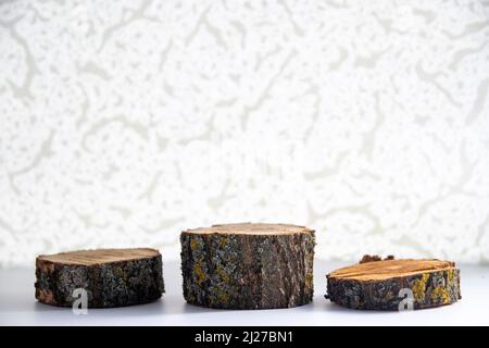 Wooden podiums from willow covered with moss on a light background. Chiaroscuro pattern, layout or stand. Stock Photo