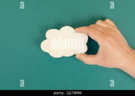 Holding a white cloud in the hand, empty copy space for text, green background, communication and marketing concept, being connected, networking Stock Photo