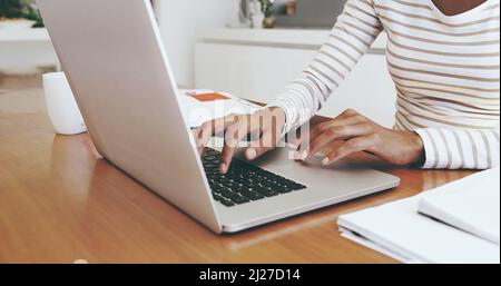I have to work from home today. Shot of an unrecognizable womans hands typing on a laptop while being seated next to a table at home. Stock Photo