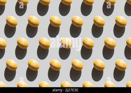 Seamless pattern with Easter eggs, repeating painted yellow eggs with a hard shadow on a gray background, Easter background in pop art style Stock Photo
