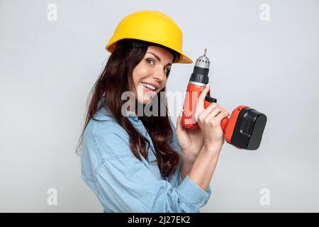 Young attractive brunette with an electric drill and yellow helmet Stock Photo