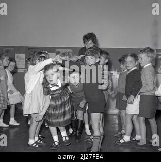 1960s, London, primary school children playing a game outside in the ...