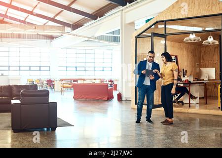 Its a big space to get creative. Shot of two designers working on a digital tablet together in an office. Stock Photo