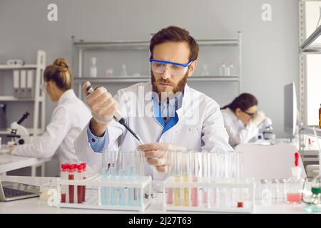 Serious male scientist is working on analysis of samples while working in laboratory. Stock Photo