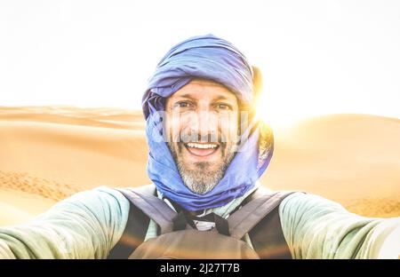 Young man solo traveler taking selfie at Erg Chebbi desert dune near Merzouga in Morocco - Adventure wanderlust concept on world famous nature wonder Stock Photo