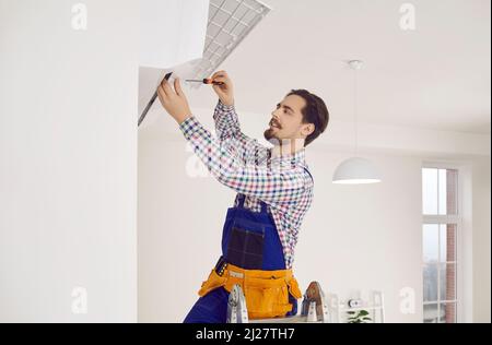 Young male professional repairman installs new air conditioner in client's apartment. Stock Photo