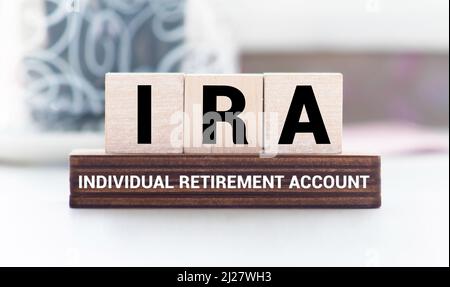 IRA individual retirement account word on wood cube block with blue background. Stock Photo