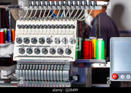 Modern electronic professional embroidery machine using preset programs for embroidery with multi-colored threads. Selective focus. Copy space. Stock Photo