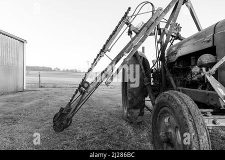 An old antique hedge trimmer mounted on a vintage tractor Stock Photo