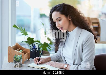 These notes will come in handy. Shot of a young businesswoman taking notes. Stock Photo