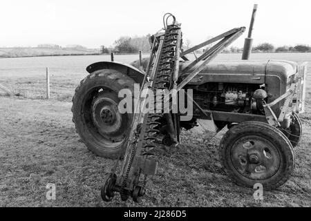 An old antique hedge trimmer mounted on a vintage tractor Stock Photo