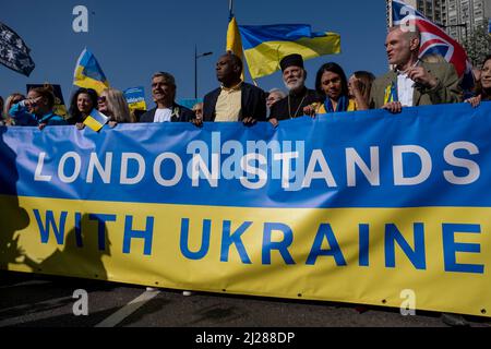 London Mayor Sadiq Khan stands alongside Labour Shadow Foreign Secretary David Lammy MP as thousands of people gather in the capital for a peace march ‘London stands with Ukraine’ in solidarity with the people of Ukraine on 26th March 2022 in London, United Kingdom. The conflict in Ukraine is now in it’s second month and their president has called for people across the World to unite in protest at the Russian invasion and ongoing war in the region. The Ukrainian flag of yellow and blue was everywhere to be seen in this colourful show of unity. Stock Photo