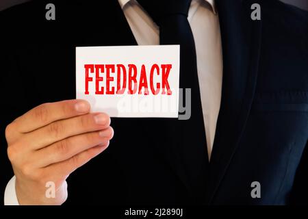 FEEDBACK word on the card shown by a man, vintage tone. Stock Photo