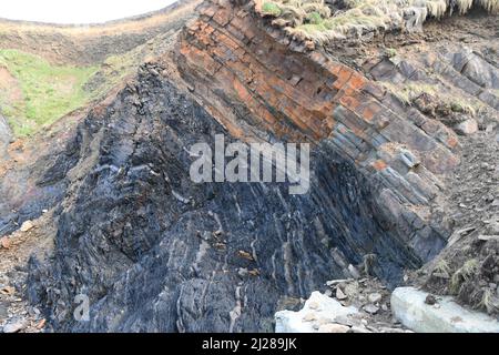 Sandymouth bay with rugged distorted,strata of sandstone and dark shale beds dip defining a syncline.On the Atlantic coast of north Cornwall. England. Stock Photo