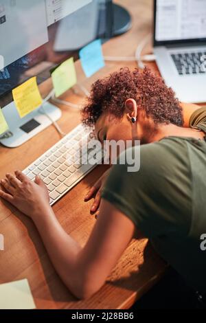 Shes been burning the candle at both ends. Shot of an exhausted young businesswoman sleeping with her head on her desk. Stock Photo