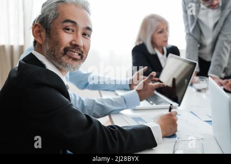 Business senior Asian man smiling at camera while working inside bank office - Focus on face Stock Photo