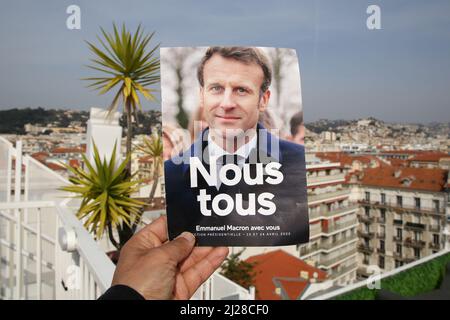 Nice, France. 29th Mar, 2022. A man holds Emmanuel Macron's presidential election 2022 leaflet with a view of properties in Nice. The first round of the French Presidential Election 2022 will take place on Sunday 10th April 2022. Credit: SOPA Images Limited/Alamy Live News Stock Photo