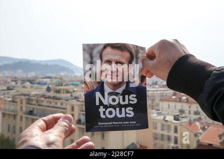 Nice, France. 29th Mar, 2022. A man holds Emmanuel Macron's presidential election 2022 leaflet with a view of properties in Nice. The first round of the French Presidential Election 2022 will take place on Sunday 10th April 2022. Credit: SOPA Images Limited/Alamy Live News Stock Photo